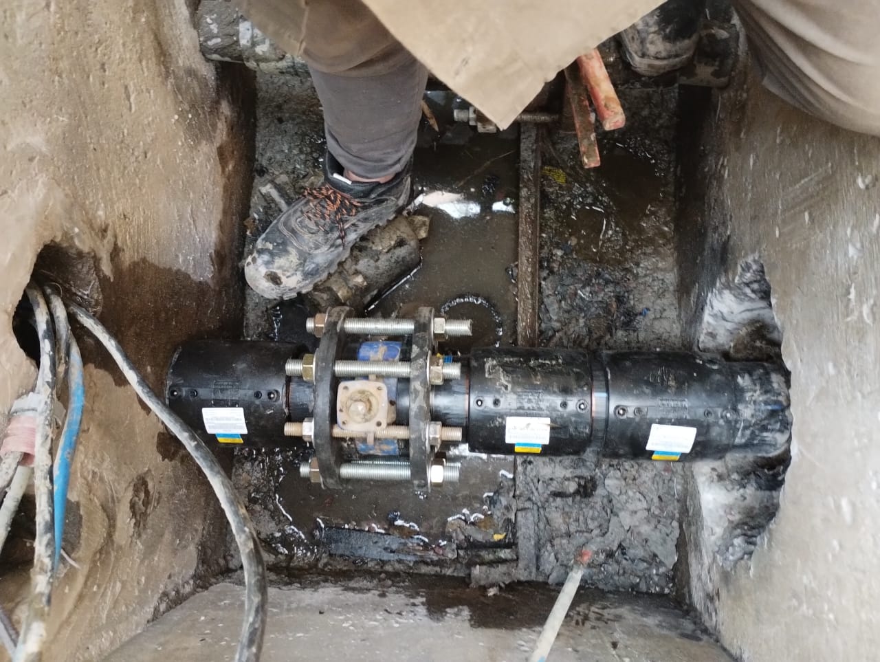 Primer plano de una unión con brida en cañería PEAD instalada bajo tierra.